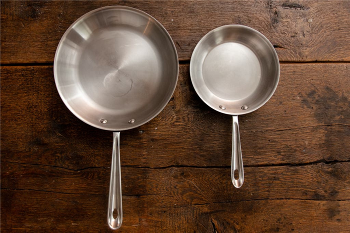 Две вымытые сковороды из нержавеющей стали, обе выглядят блестящими и почти не имеют жирных пятен.